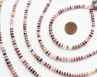 May include: A strand of multi-colored gemstone beads, including pink, red, purple, and clear, with a variety of shapes and sizes. The beads are strung on a white cord and are approximately 4mm in diameter. The beads are displayed in a circular pattern on a white background.