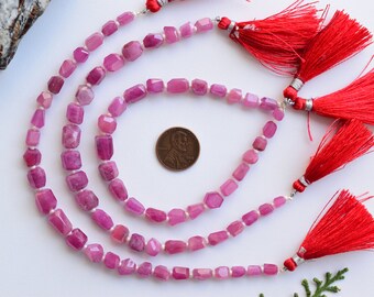 May include: Three strands of pink ruby gemstone beads with silver clasps and red tassels. The beads are faceted and have a rectangular shape. A US penny is included for size reference.