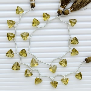 May include: A strand of faceted, triangular lemon quartz gemstones linked by silver-toned metal wire. The strand features a dark brown silk tassel at the end, with each gemstone individually spaced along the wire to create a delicate, dangling arrangement.