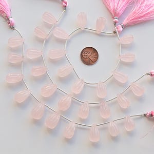 Puede incluir: Un hilo de cuentas de piedra preciosa de cuarzo rosa, de color rosa, enhebradas en un alambre plateado, con borlas rosas en cada extremo. Las cuentas son facetadas y tienen forma de lágrima.
