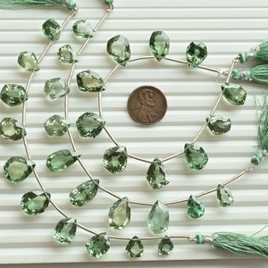 Könnte beinhalten: Eine Kette aus grünen Edelsteinperlen mit silbernem Draht und grünen Quasten. Die Perlen sind birnenförmig und haben eine facettierte Oberfläche. Die Kette ist etwa 45 cm lang.