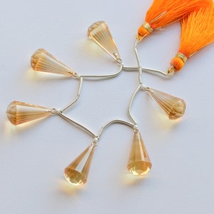 May include: A strand of faceted teardrop-shaped topaz beads with silver connectors and two orange tassels.