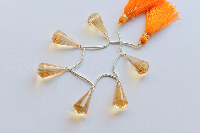 May include: A strand of faceted teardrop-shaped topaz beads with silver connectors and two orange tassels.