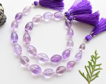 May include: A strand of light purple amethyst beads with a faceted oval shape. The beads are strung on a silver wire and have purple tassels on each end.