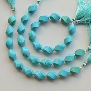 May include: Three strands of turquoise beads with a faceted, oval shape. Each strand has a turquoise tassel at the end.
