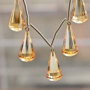 May include: A necklace with a silver chain and multiple teardrop-shaped amber crystals.