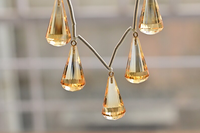 May include: A necklace with a silver chain and multiple teardrop-shaped amber crystals.