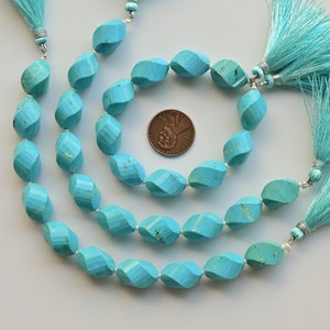 May include: Three strands of turquoise beads with a faceted, twisted design. The beads are a vibrant blue-green colour and are strung on a silver cord. Each strand has a turquoise tassel at the end.