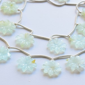 May include: A silver chain necklace with light blue flower-shaped gemstone beads.