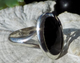 Op de afbeelding: Een zilveren ring met een zwarte ovale edelsteen. De ring is gemarkeerd met "925" aan de binnenkant van de band.