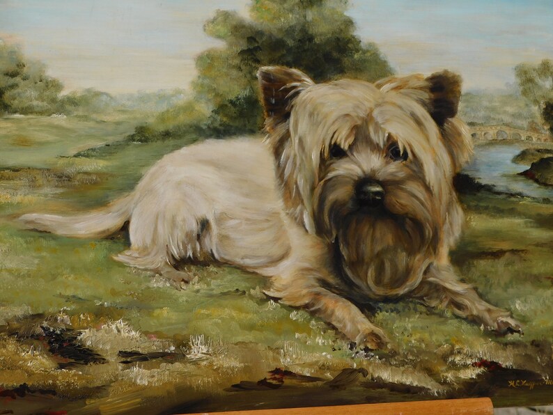 May include: A painting of a small, white dog with brown fur on its face and ears. The dog is lying down on a grassy field with a bridge and trees in the background.