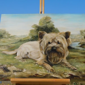 May include: A painting of a small, light brown dog with a fluffy coat, lying down in a grassy field. The dog is looking directly at the viewer. The painting is set against a backdrop of a blue sky and green trees.
