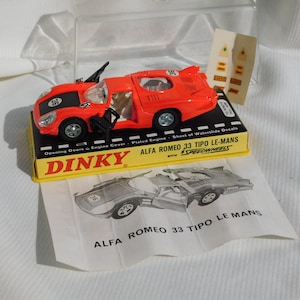 Op de afbeelding: Een rode Dinky Toys Alfa Romeo 33 Tipo Le-Mans raceauto met openende deuren en een verchroomde motor. De auto zit in de originele doos met een vel waterslide-decals.