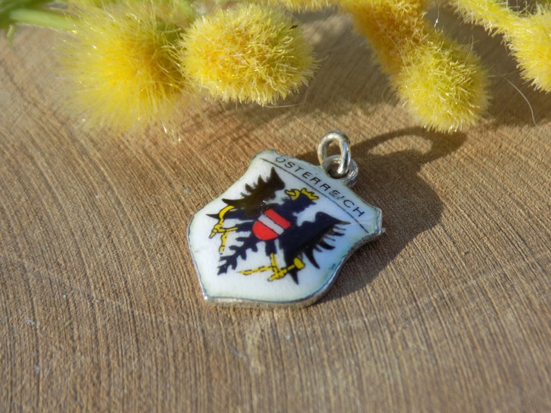 K&ouml;nnte beinhalten: Ein kleiner, schildf&ouml;rmiger Anh&auml;nger mit dem Wort "&Ouml;STERREICH" und dem &ouml;sterreichischen Wappen. Der Anh&auml;nger zeigt einen schwarzen Adler mit einem rot-wei&szlig;em Schild auf wei&szlig;em Grund, mit einer silberfarbenen &Ouml;se.