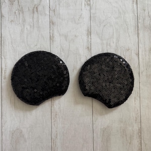 May include: Two black sequined mouse ears. The ears are made of black sequins and have a rounded shape.