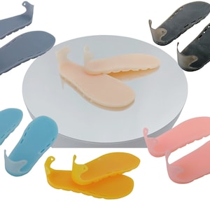May include: Assortment of six pairs of 3D printed orthotic shoe inserts in various colors, including blue, pink, yellow, beige, and gray. The inserts have a raised heel and a strap that goes around the ankle.