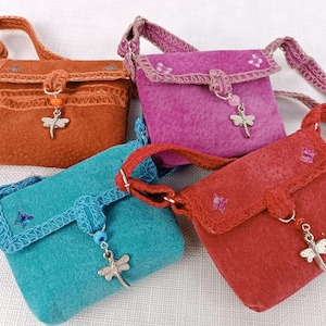 May include: Four small, colorful felt purses with dragonfly charms. Each purse has a different color: orange, pink, blue, and red. The purses have a flap closure and a strap.