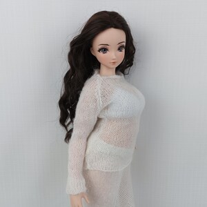 May include: A doll with long, dark brown wavy hair, wearing a sheer, light pink and white knit sweater and matching skirt. The doll has a fair complexion and is posed against a plain white background.