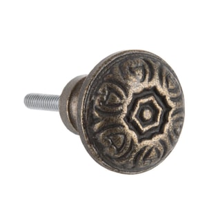 Puede incluir: Un pomo de armario decorativo de hierro fundido con un diseño floral detallado en un acabado bronce oscuro.