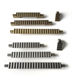 May include: A set of six decorative cabinet pulls in two finishes. Three pulls are a brushed nickel finish and three pulls are a brass finish. The pulls have a ribbed design and are rectangular in shape.