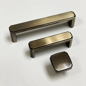 May include: Three antique gold cabinet pulls with a brushed finish. The largest pull is 6 inches long, the middle pull is 4 inches long, and the smallest pull is 1.5 inches in diameter.