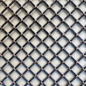 May include: Black metal mesh with copper accents. The mesh is woven in a diamond pattern.