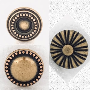 May include: Two antique gold-toned metal buttons with decorative designs. One button has a circular design with a raised center and a ring of dots around the edge. The other button has a sunburst design with radiating lines.