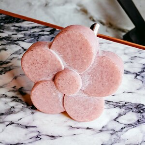 Puede incluir: Un pomo de armario en forma de flor rosa con un vástago de metal plateado.