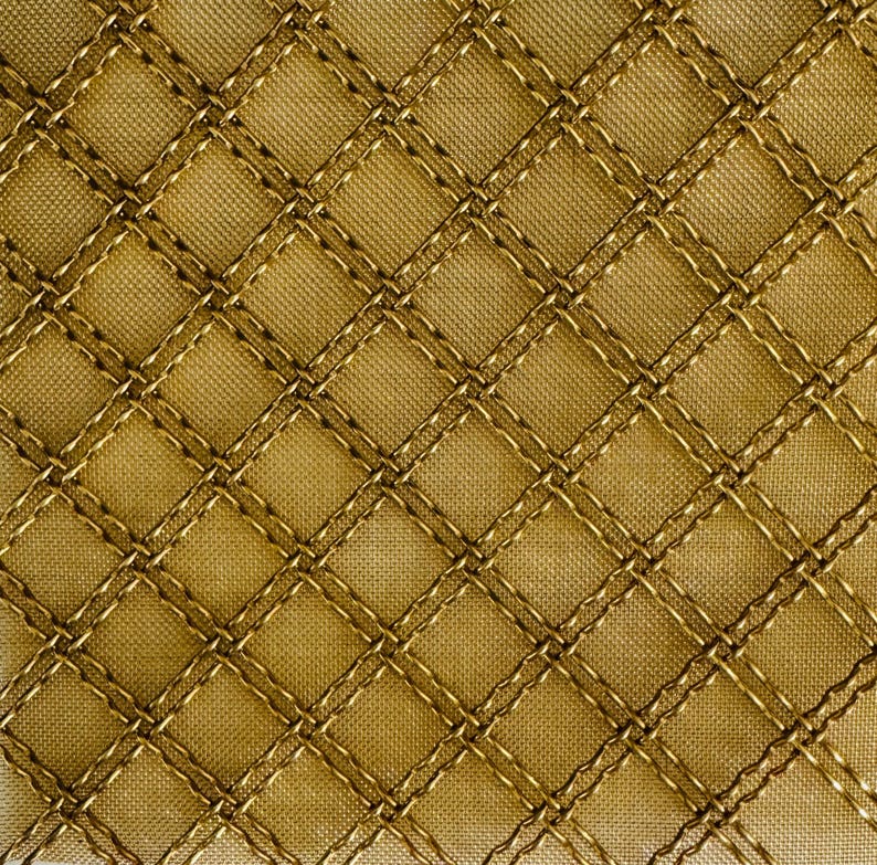 May include: A close-up of a gold fabric with a diamond pattern created by stitching. The fabric has a subtle sheen.