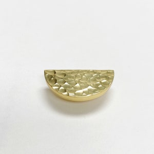 May include: A gold hammered half-circle cabinet pull.