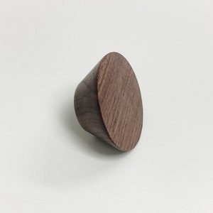 May include: A dark brown wooden knob with a rounded, slightly conical shape. The knob has a smooth, polished finish and a natural wood grain pattern.