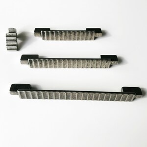 May include: Three silver metal cabinet pulls with a textured, ribbed design. The pulls are different sizes.