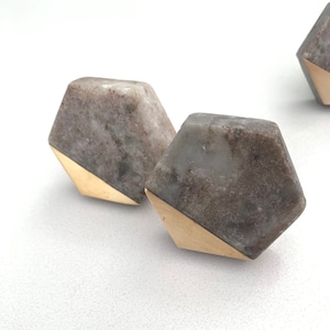 May include: Two hexagonal cabinet knobs with a gray and white marbled finish and a gold metal trim.
