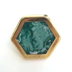 May include: A hexagonal gold-toned frame surrounds a green and white marbled resin cabochon.