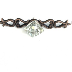 May include: A decorative cabinet pull with a clear crystal diamond knob and an ornate bronze metal base.
