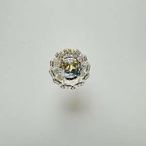 May include: A clear glass door knob with a gold metal frame. The knob has a faceted design and a star-shaped center.