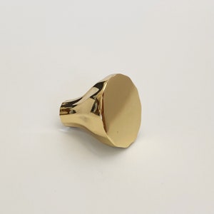 May include: A gold-toned cabinet knob with a rounded, slightly scalloped design.