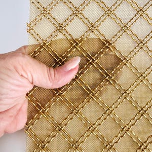 May include: Gold metal mesh with a diamond pattern. The mesh is flexible and has a woven texture.