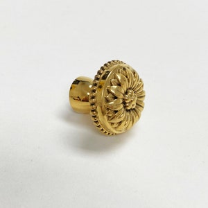 May include: A gold-toned door knob with a decorative floral design.