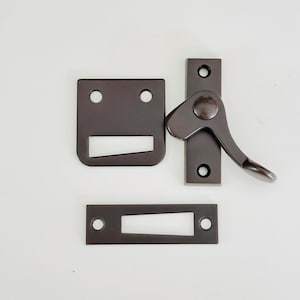 May include: A set of three bronze window sash locks. The locks are made of metal and have a simple, functional design. The set includes a lever handle, a strike plate, and a keeper.