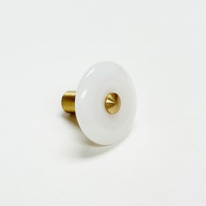 May include: White ceramic knob with a brass center, perfect for adding a touch of modern style to cabinets or drawers.