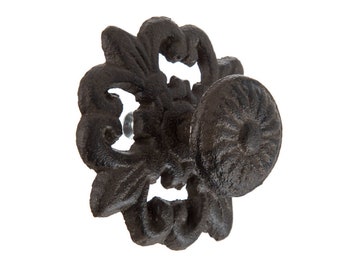 May include: Black cast iron hook with a decorative floral design. The hook is shaped like a flower with a round knob in the centre.