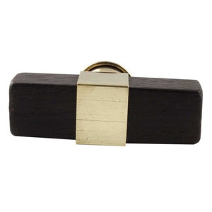 May include: A dark wood cabinet knob with a brass centre and a square brass plate.