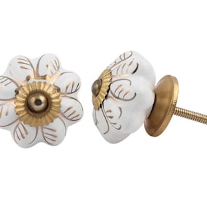 Könnte beinhalten: Weißer Keramik-Knopf für Schränke mit goldenem Blumendesign und goldener Metallschraube.