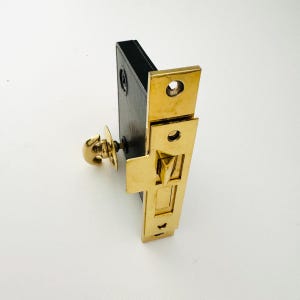 Può includere: Una serratura per porte dorata con una manopola decorativa e una maniglia a leva. La serratura ha una piastra di fondo in metallo nero.