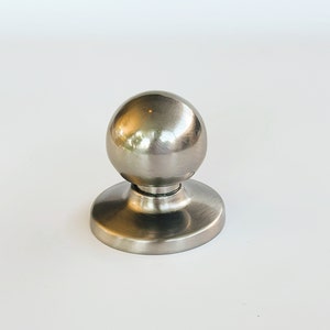 May include: A silver round door knob with a smooth, shiny finish.