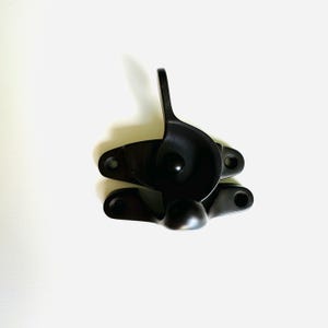 Könnte beinhalten: Schwarzes Fensterflügel-Schloss mit einem Hebelgriff. Das Schloss hat eine runde, kreisförmige Form und ist aus Metall.