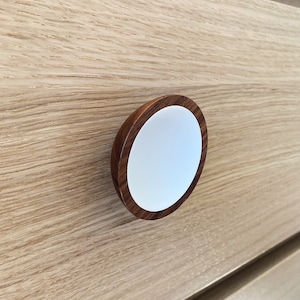 May include: A wooden drawer pull with a white center and a dark brown rim.