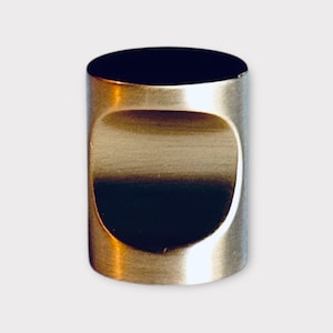 May include: A brushed nickel cabinet knob with a round, recessed handle. The knob is cylindrical in shape.