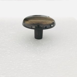 May include: A round, dark brown cabinet knob with a shiny finish. The knob has a short, black stem.